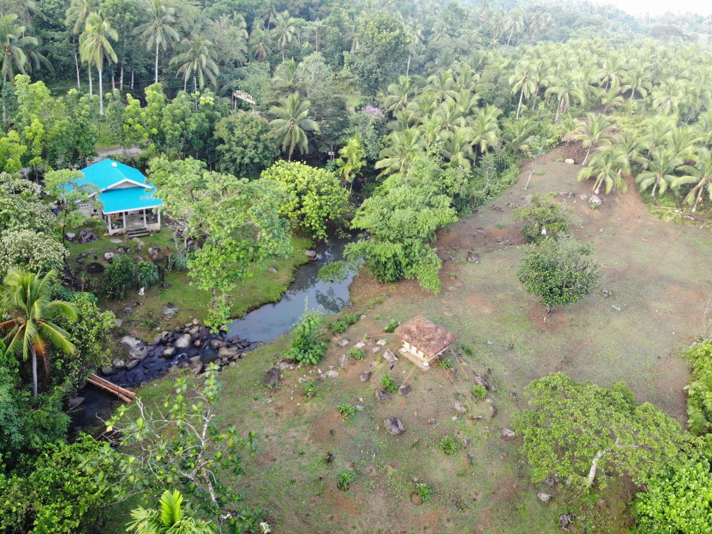 Aerial view of the farm with the blue-roof house beside the creek