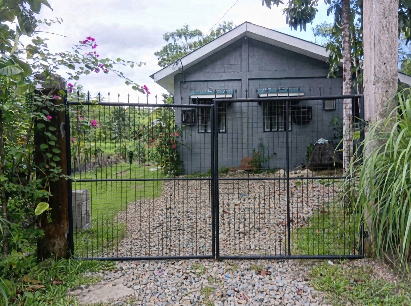 House behind a black metal gate with gravel drive